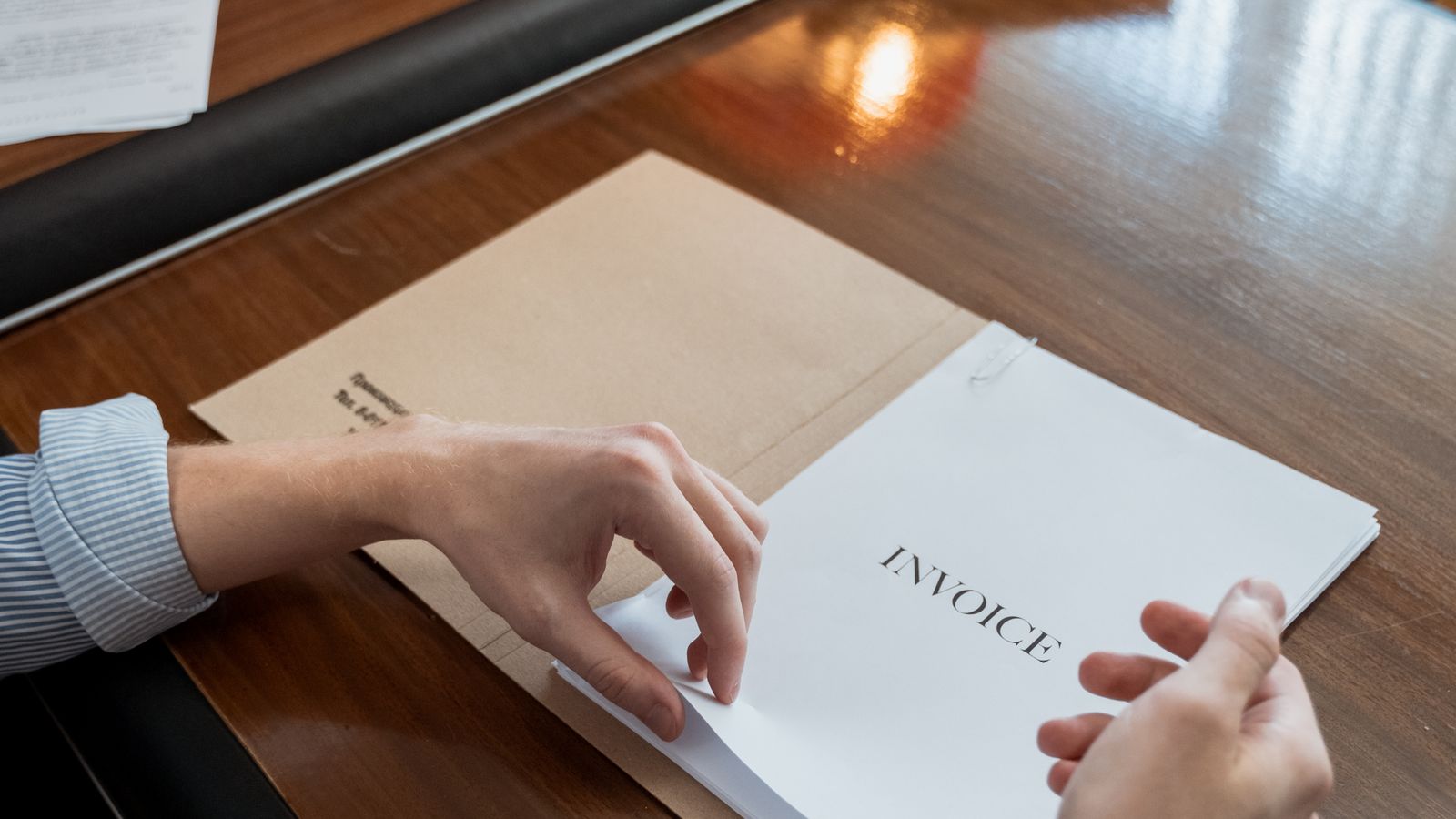 Personne classant une facture et des documents administratifs sur un bureau